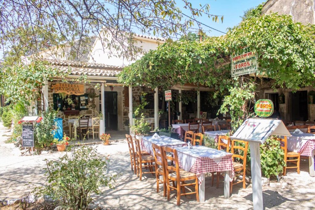Traditional taverna in Old Perithia, Corfu with outdoor tables under green vines